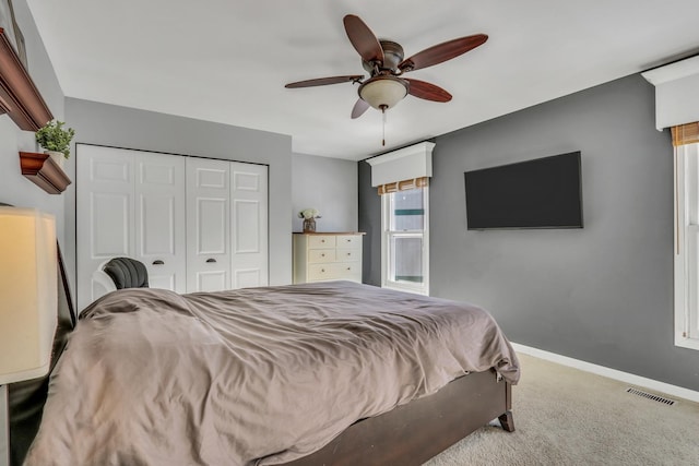 carpeted bedroom with a closet, visible vents, a ceiling fan, and baseboards