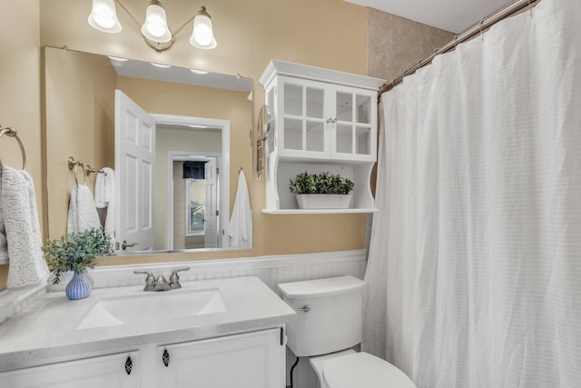 bathroom with wainscoting, toilet, a shower with curtain, and vanity