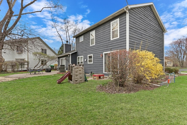 back of house featuring a lawn, a chimney, and a patio area