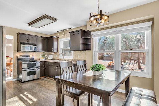 kitchen featuring dark brown cabinetry, a chandelier, stainless steel appliances, and tasteful backsplash