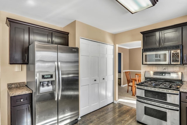 kitchen featuring light stone counters, decorative backsplash, baseboards, appliances with stainless steel finishes, and dark wood-style floors