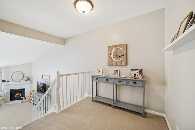 hallway with baseboards, light carpet, and an upstairs landing