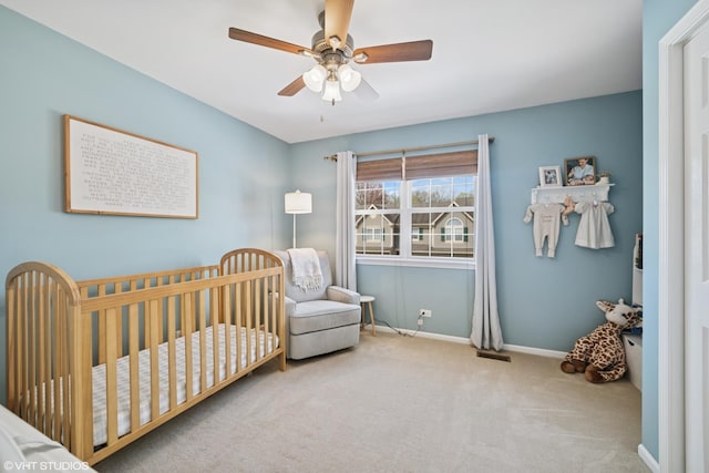 carpeted bedroom featuring a nursery area, baseboards, a ceiling fan, and visible vents