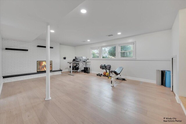 exercise area with recessed lighting, wood finished floors, a brick fireplace, and visible vents