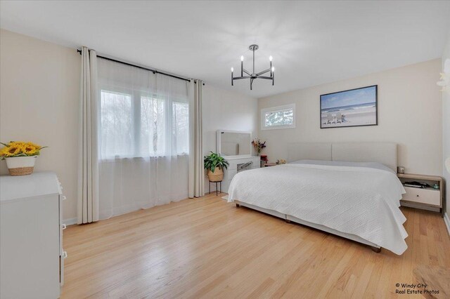 bedroom featuring light wood-type flooring and an inviting chandelier