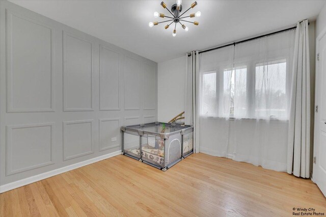 empty room with light wood-type flooring and an inviting chandelier