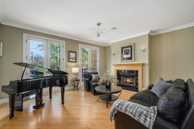sitting room featuring light wood-style floors, ornamental molding, a fireplace, a chandelier, and baseboards