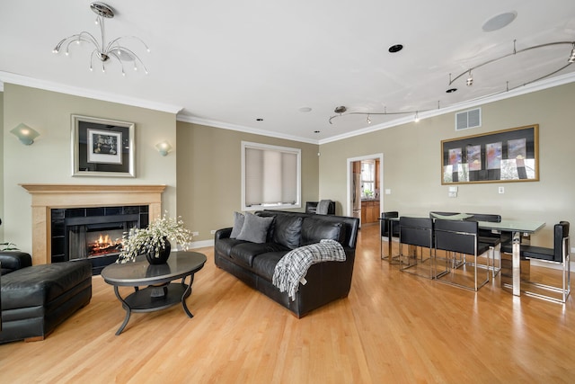 living area featuring wood finished floors, crown molding, track lighting, baseboards, and a tiled fireplace