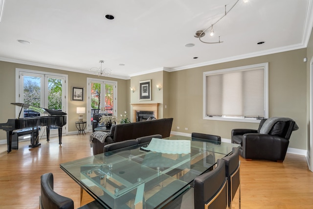 dining room featuring light wood-style flooring, baseboards, a fireplace, ornamental molding, and a chandelier