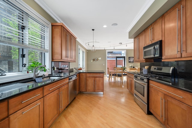 kitchen featuring appliances with stainless steel finishes, brown cabinets, light wood finished floors, decorative backsplash, and crown molding