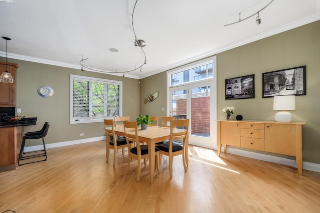 dining area with ornamental molding, light wood-style flooring, and baseboards