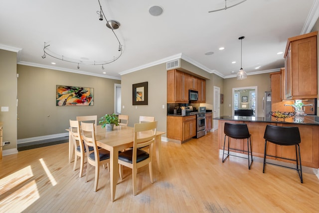 dining room with light wood finished floors, recessed lighting, ornamental molding, baseboards, and track lighting