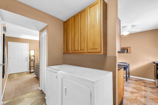 clothes washing area with baseboards, separate washer and dryer, cabinet space, and a textured ceiling