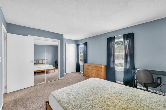 carpeted bedroom with a textured ceiling, a closet, and baseboards