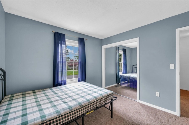 carpeted bedroom featuring baseboards and a closet