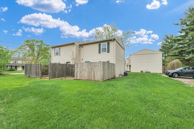 rear view of property featuring cooling unit, a yard, and fence