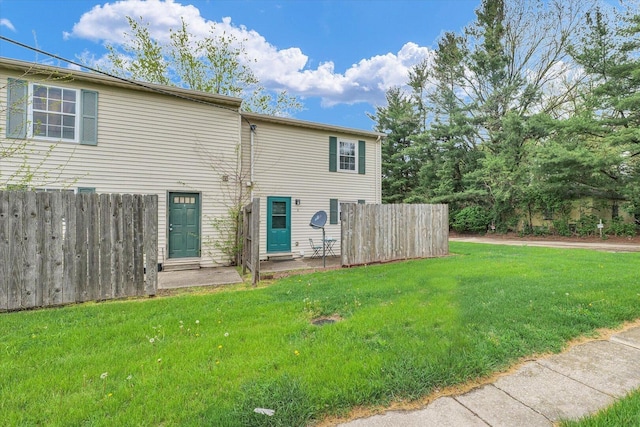 rear view of property featuring fence and a yard