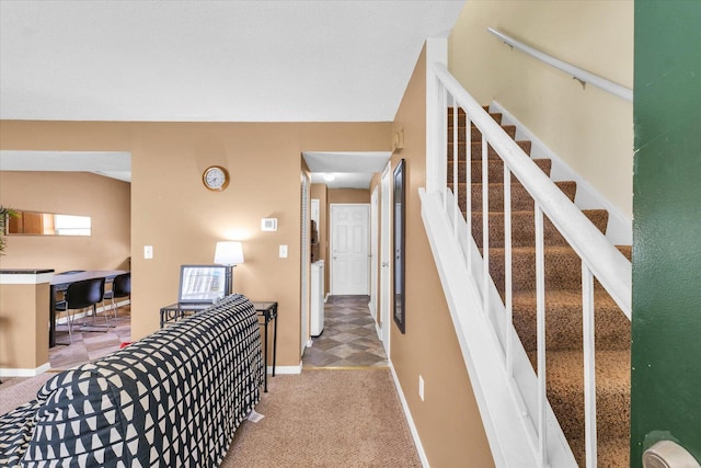 hallway with stairs, light carpet, and baseboards