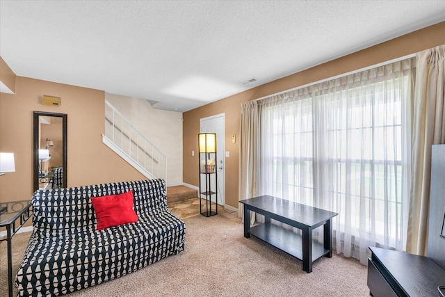living room with baseboards, visible vents, light carpet, and stairs