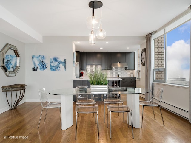 dining room with a baseboard heating unit, baseboards, wood finished floors, and recessed lighting