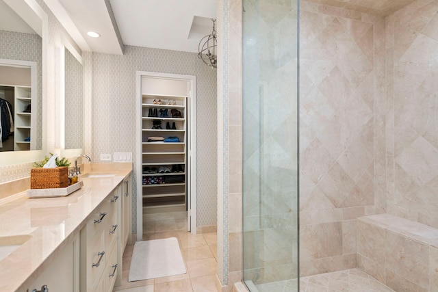 full bathroom featuring wallpapered walls, a spacious closet, tiled shower, and a sink