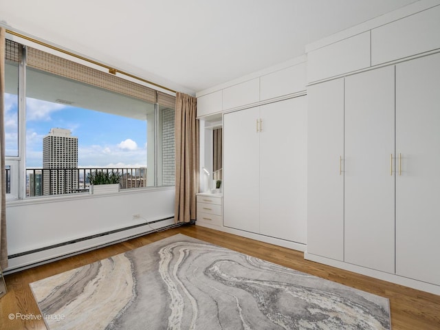 unfurnished bedroom featuring a baseboard radiator and wood finished floors