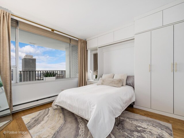 bedroom featuring wood finished floors and baseboard heating