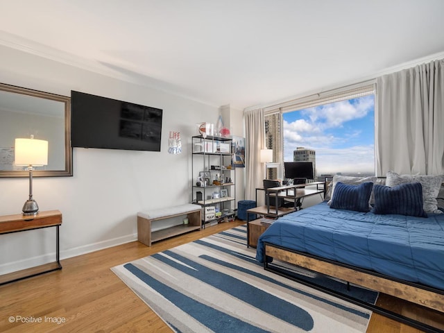 bedroom with wood finished floors, baseboards, and ornamental molding