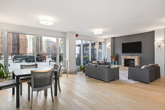 living area featuring light wood-style flooring and a stone fireplace