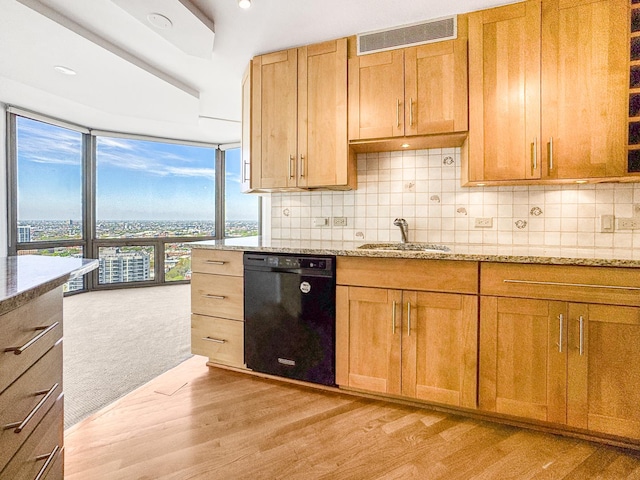 kitchen featuring black dishwasher, a sink, light stone counters, light wood-style flooring, and floor to ceiling windows