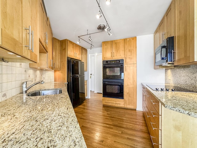 kitchen with black appliances, a sink, light stone countertops, dark wood finished floors, and tasteful backsplash