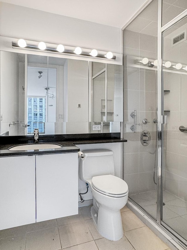bathroom with a stall shower, vanity, tile patterned flooring, and toilet