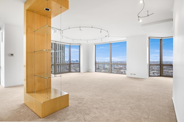 unfurnished living room with expansive windows, carpet flooring, and a view of city