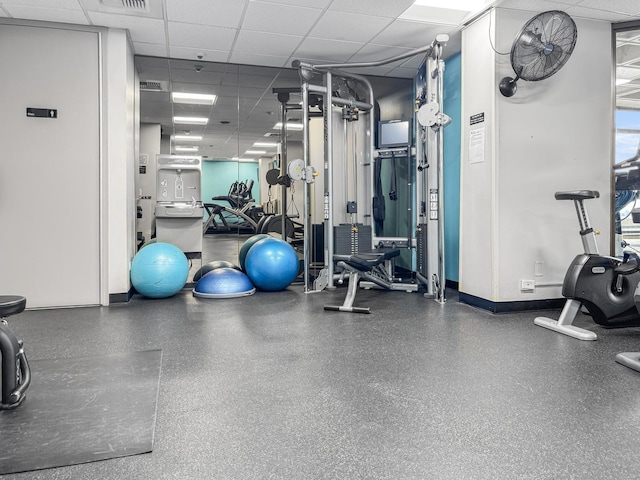 workout area with a drop ceiling and baseboards