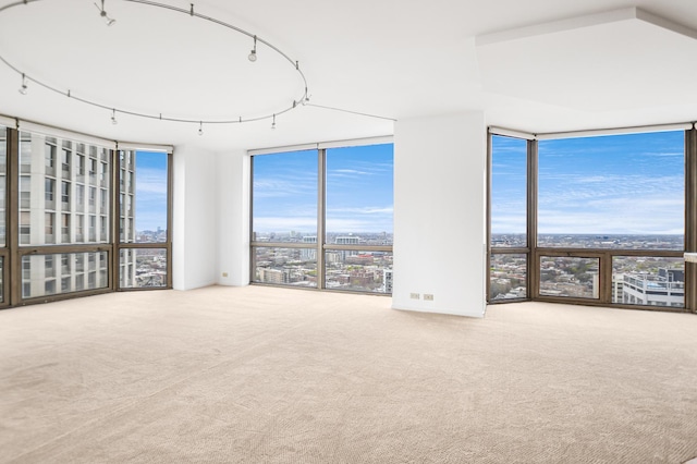 unfurnished room featuring floor to ceiling windows, carpet flooring, and a view of city