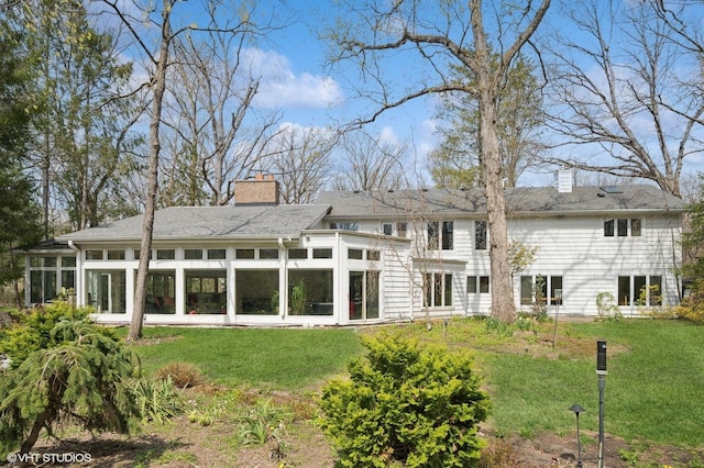 back of property featuring a sunroom, a yard, and a chimney