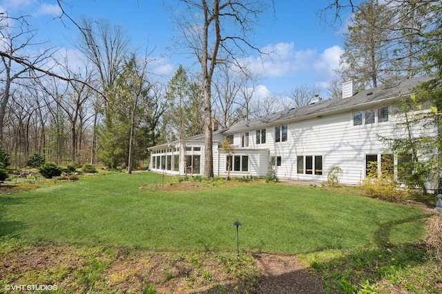 rear view of house featuring a lawn and a chimney