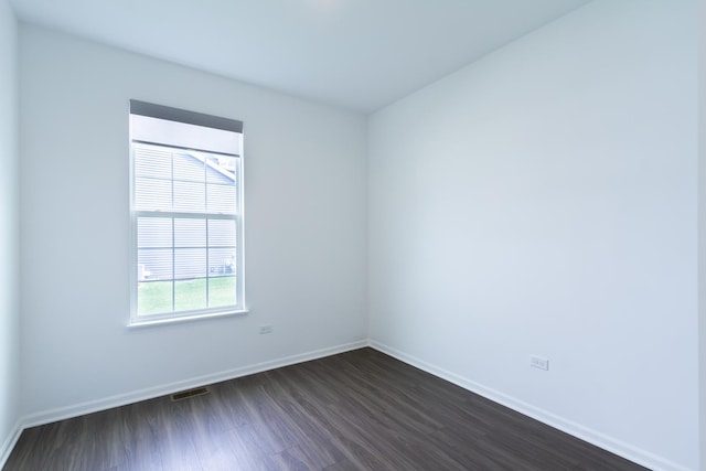 unfurnished room featuring baseboards, visible vents, and dark wood-style flooring
