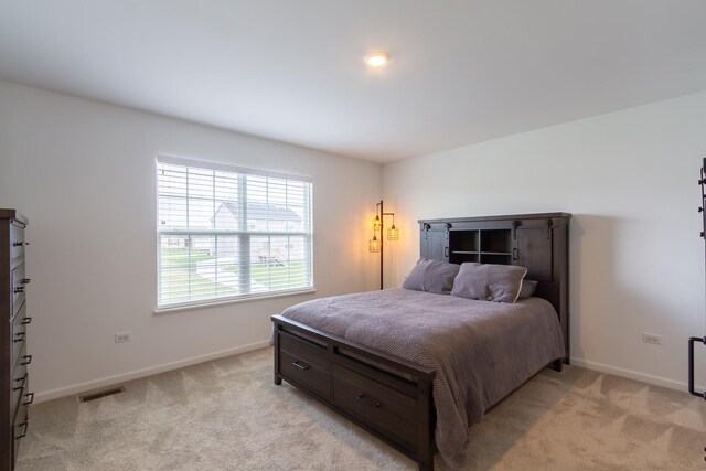 bedroom with baseboards, visible vents, and light colored carpet