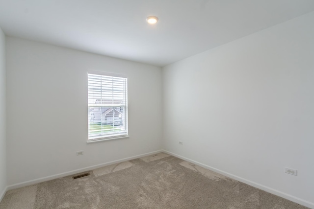 carpeted spare room with visible vents and baseboards