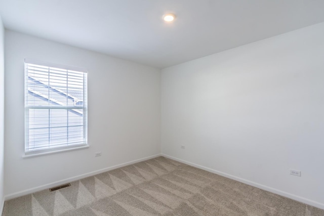 spare room with visible vents, baseboards, and light carpet