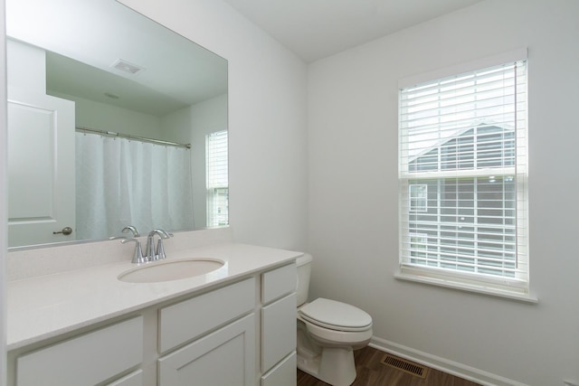 full bath with toilet, vanity, wood finished floors, and visible vents
