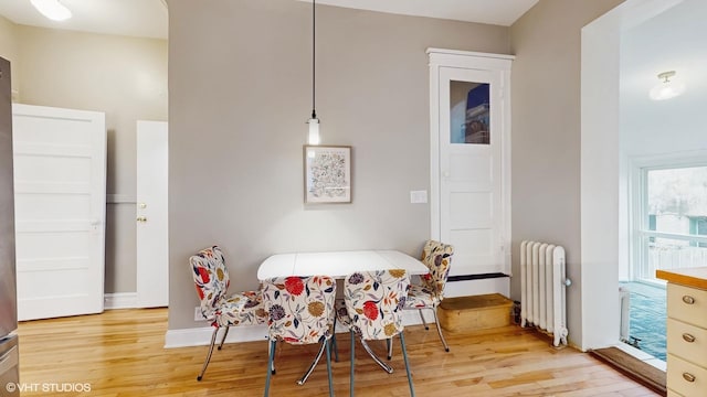 dining area with radiator, light wood-style flooring, and baseboards