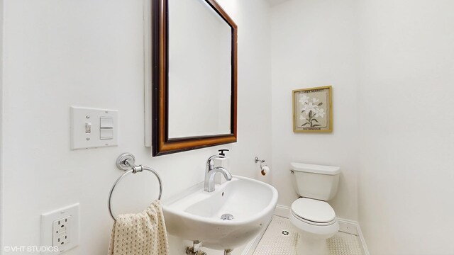 bathroom with toilet, tile patterned floors, a sink, and baseboards