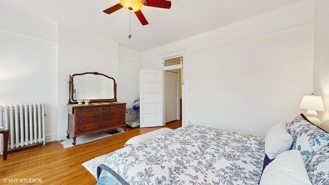 bedroom with radiator heating unit, a ceiling fan, and light wood finished floors