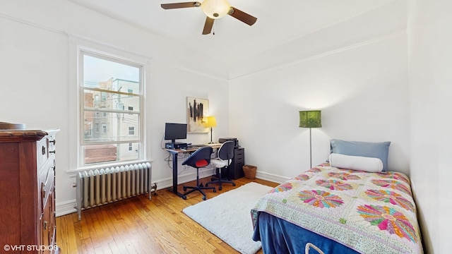 bedroom with wood-type flooring, radiator heating unit, a ceiling fan, and baseboards