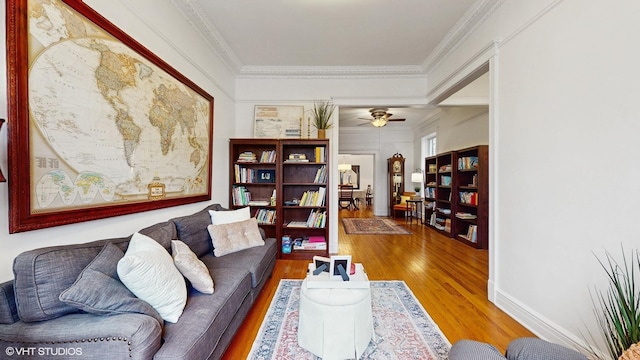 living area featuring a ceiling fan, wood finished floors, and crown molding