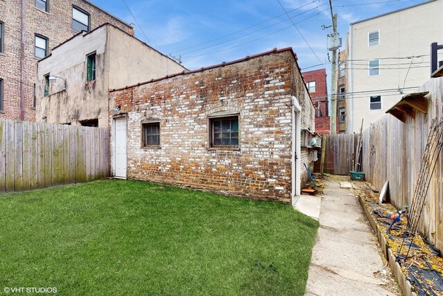 exterior space with a fenced backyard, brick siding, and a yard