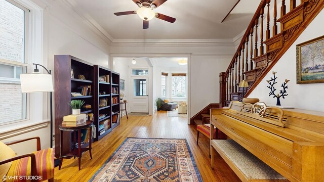 interior space with stairway, wood-type flooring, a ceiling fan, and ornamental molding