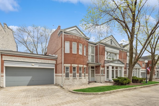 view of front facade featuring brick siding, decorative driveway, and a garage